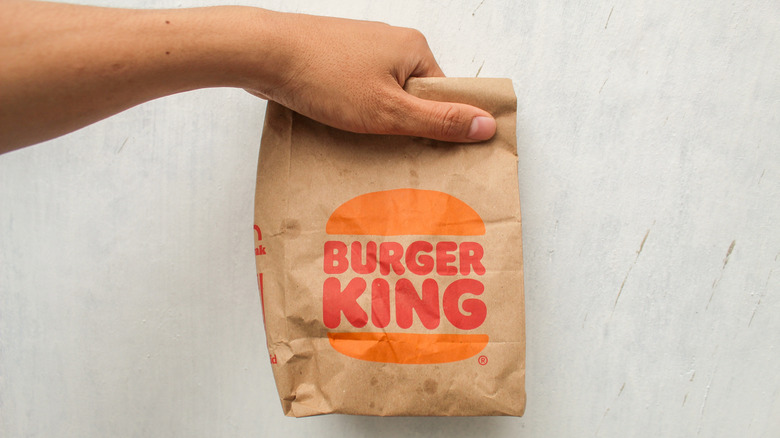 A hand holding a bag of Burger King