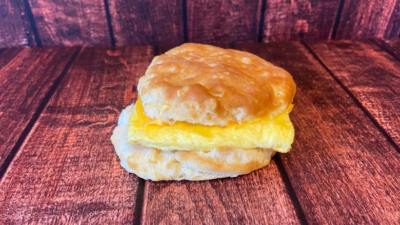 An egg, cheese, and bacon biscuit on a wooden table