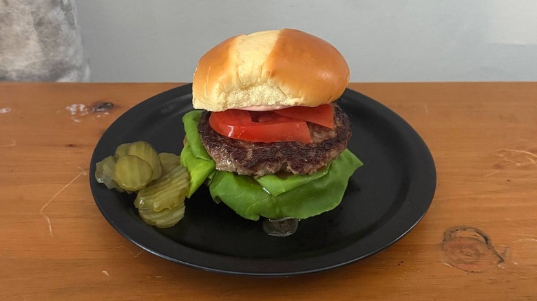 Dressed burger with a side of pickles