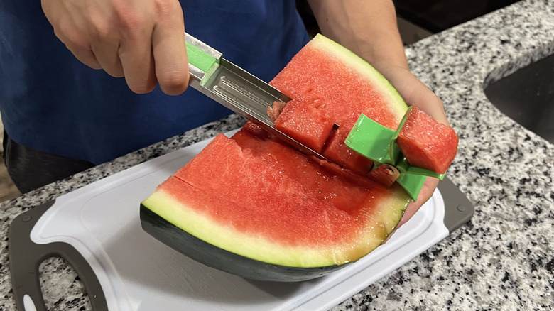 person cutting watermelon with cuber