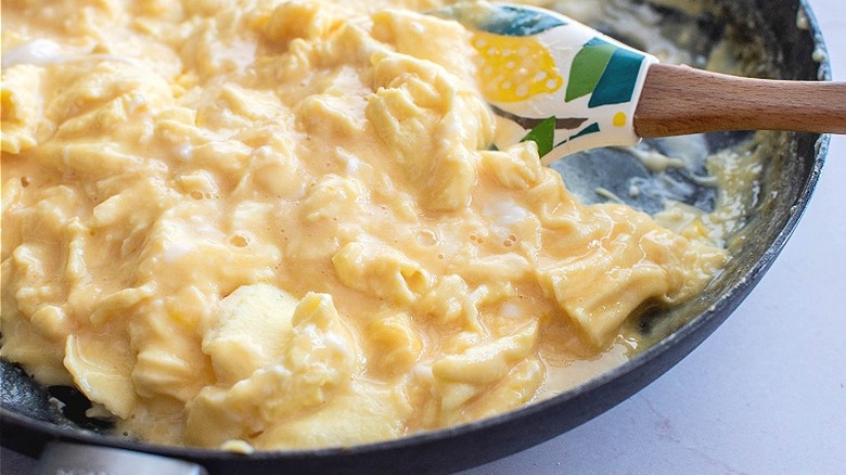 spatula stirring scrambled eggs in skillet