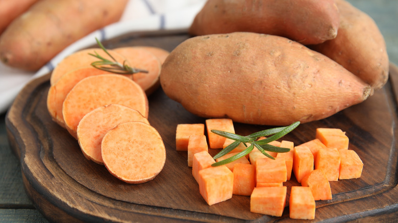 Cubed, sliced, and whole sweet potato on wooden board