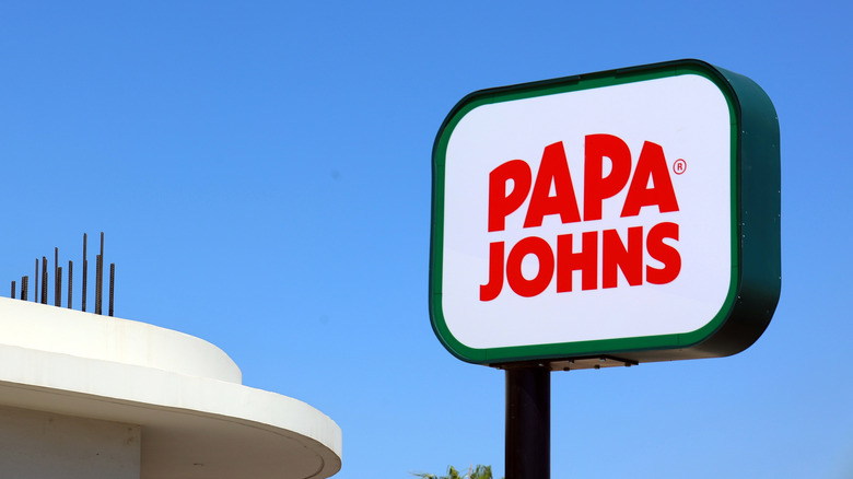 A Papa John's roadside sign is seen against a blue sky