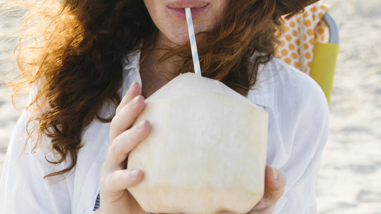 Woman drinking from coconut with straw