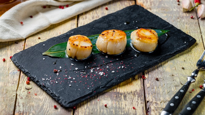 Seared scallops on a black plate