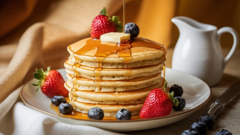 Stack of pancakes with berries and syrup drizzle