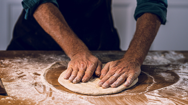 Stretching pizza dough on a floured counter top
