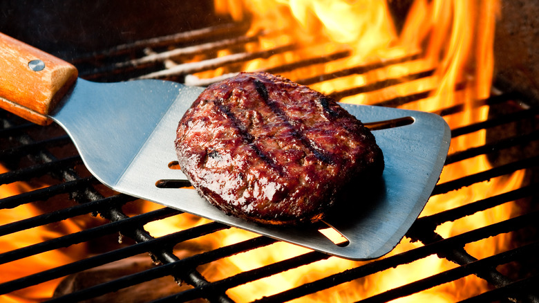 Burger on a spatula over grill