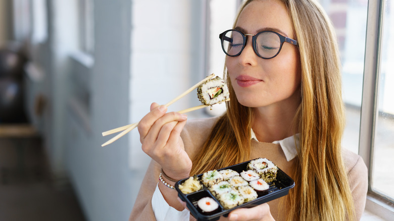 woman eating sushi with chopsticks
