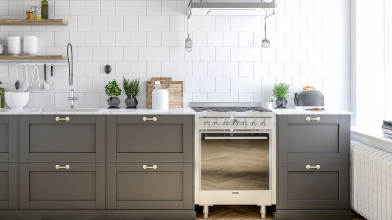 A stainless steel oven in a white kitchen with gray cabinets