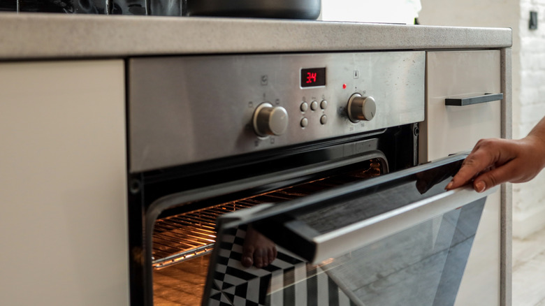A person checking on food in an oven by opening the door