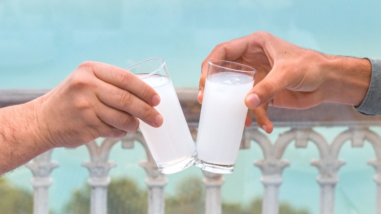hands holding glasses of Greek ouzo