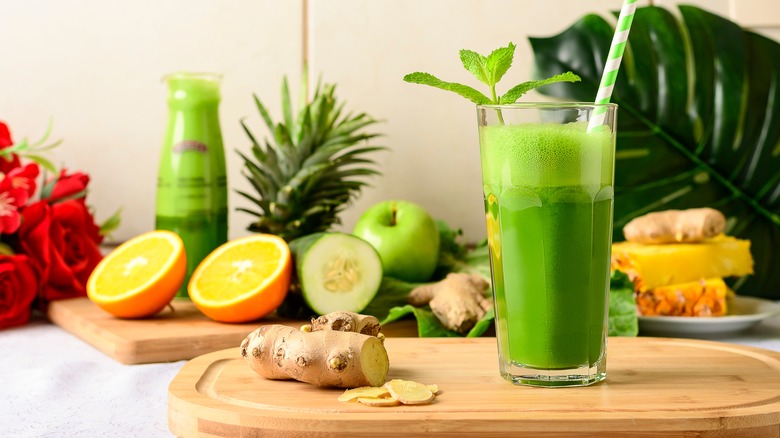 glass of green juice surrounded by ingredients