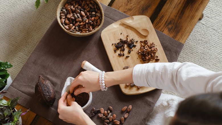 woman cracking cacao into cocoa nibs