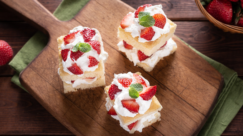 three strawberry shortcakes on a wooden board 