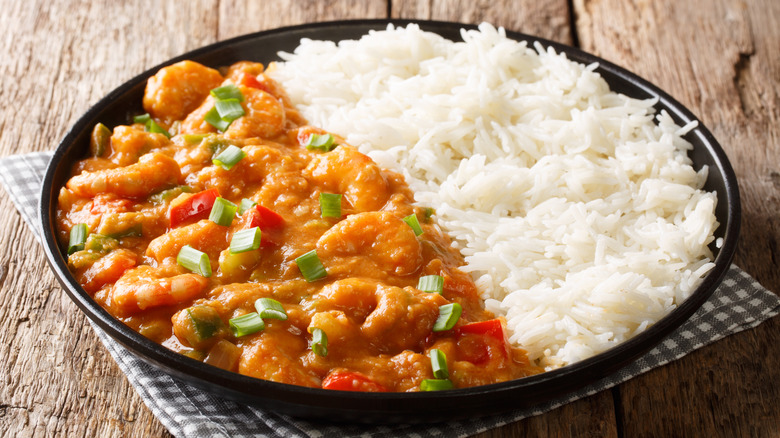 A bowl is filled with shrimp étouffée with an orange-brown sauce and white rice.