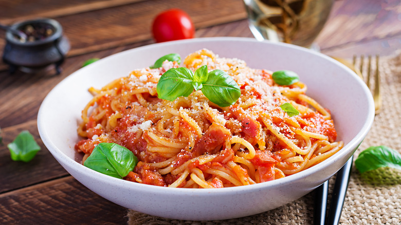 Spaghetti and sauce in a bowl with herbs and cheese