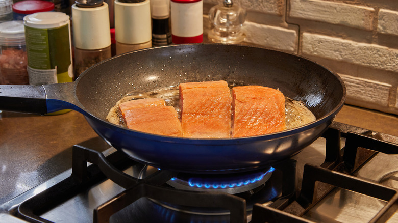 frying pan with salmon steaks cooking inside