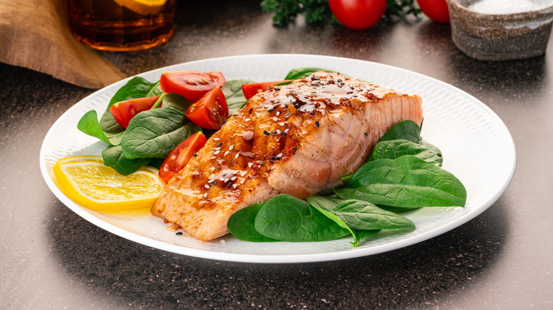 cooked salmon on place with spinach and tomatoes