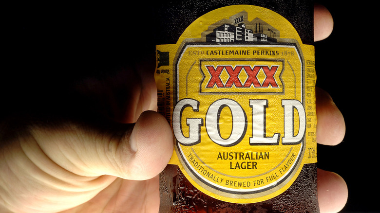 hand holding a cold bottle of xxxx Gold beer
