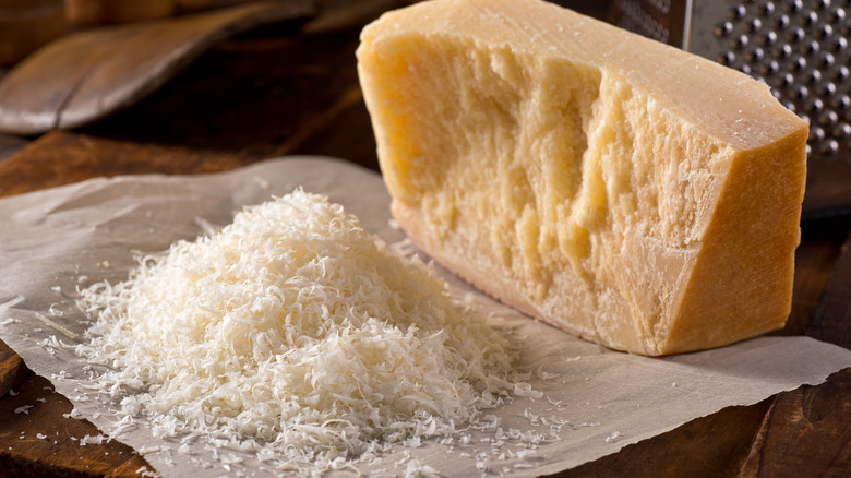 Pile of grated cheese next to block of parmesan