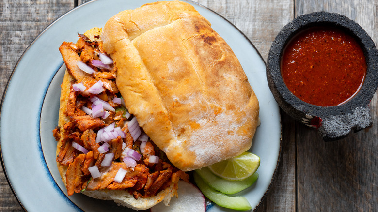 A torta al pastor with a side of salsa