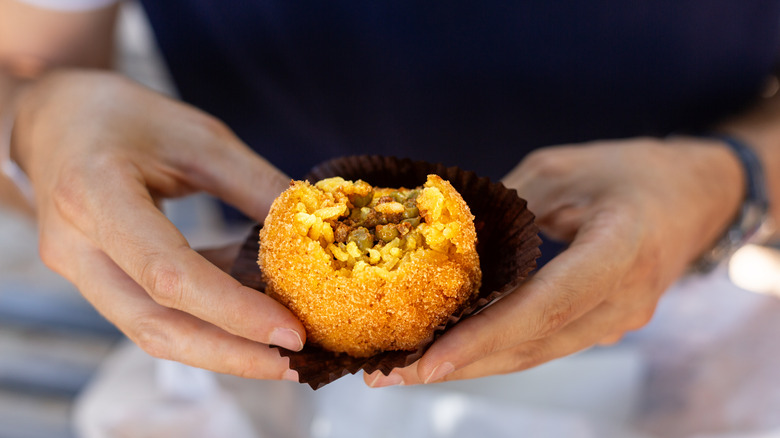 Hands holding arancini