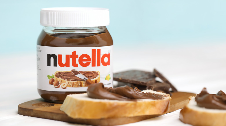 A Nutella jar with slices of bread covered in the chocolate hazelnut spread