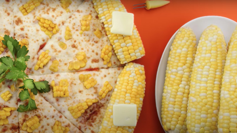 Corn cob pizza next to a plate of corn