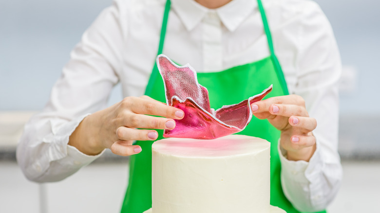 person artfully decorating a cake