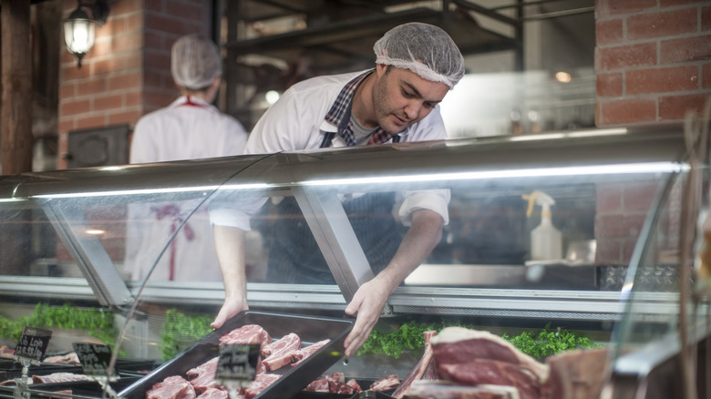 Butcher putting meat in a display case