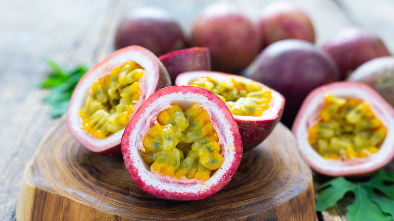 Ripe passion fruit split open on wooden serving board