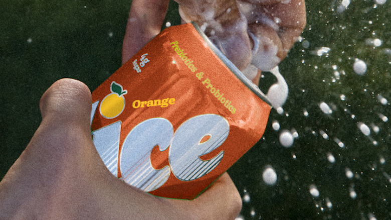 A can of Slice orange soda being opened and spraying foam