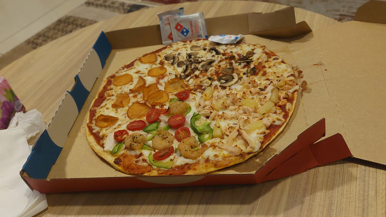 Domino's pizza with four different toppings sections in a box.