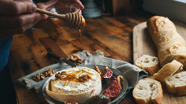 drizzling honey over baked cheese, figs, bread