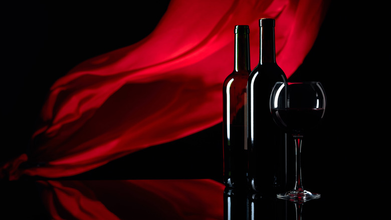 bottles and glass of wine with red tapestry background