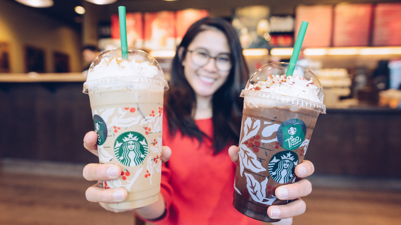 Starbucks frappes held by smiling woman in glasses
