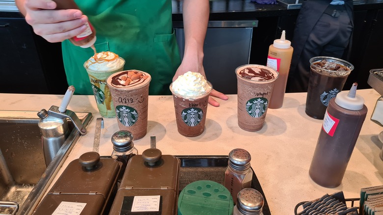 Starbucks worker puts syrup on drinks
