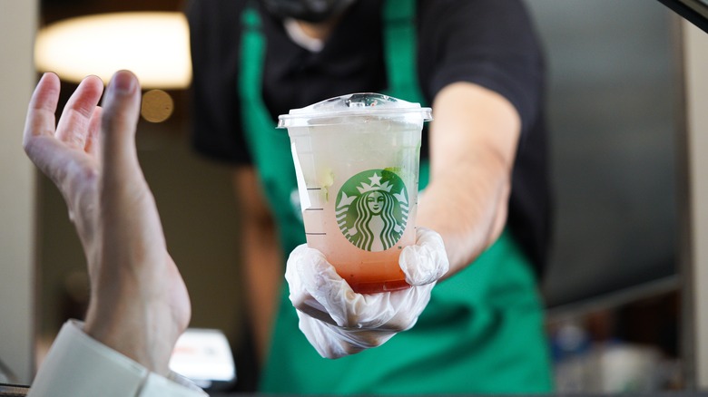Starbucks worker offering drink through drive-thru