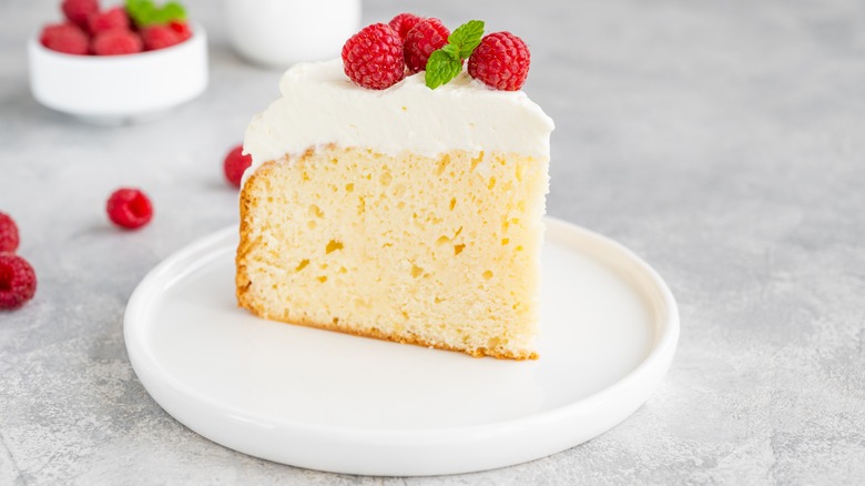 A slice of tres leches cake with whipped cream and raspberries