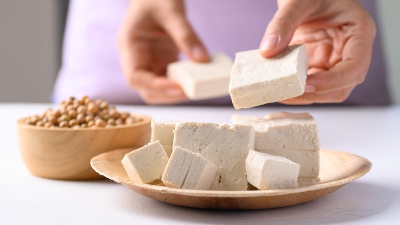 cut up block of tofu being placed on plate