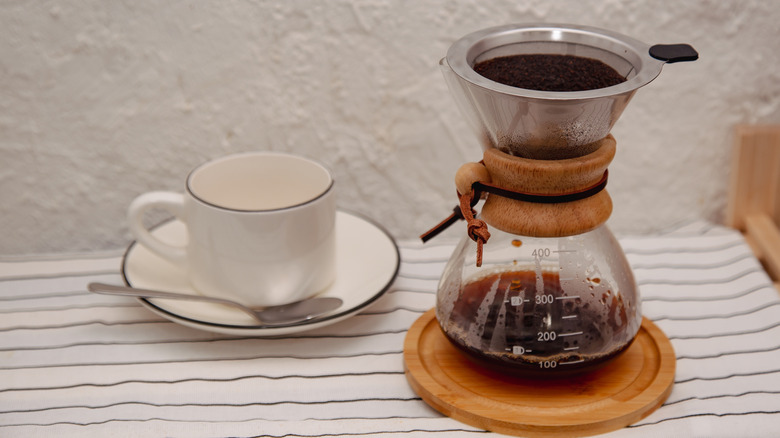 Pot of pour over coffee next to a mug