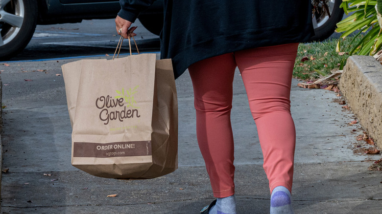 Person carrying Olive Garden bag