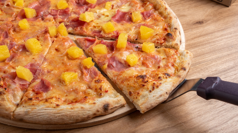 Portion of pineapple and ham pizza on wood table