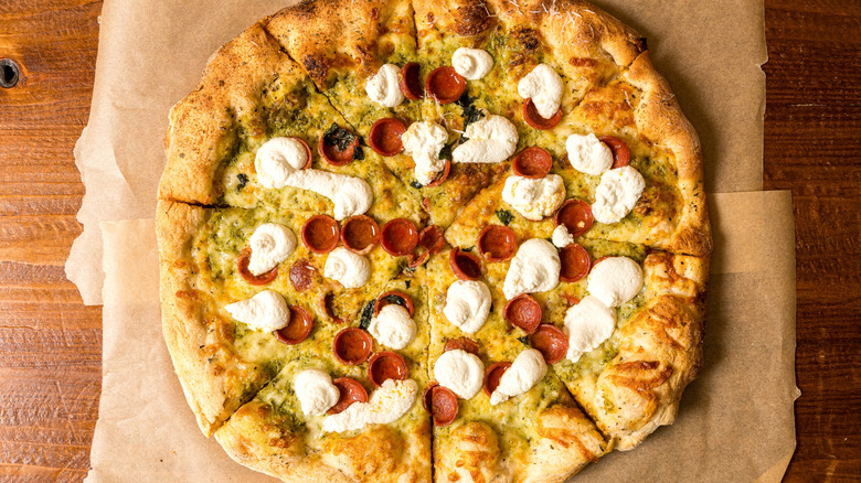 Pizza with ricotta and pepperoni on wood table