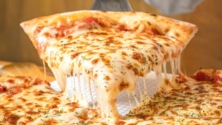 Slice of extra cheese pizza being raised from pie