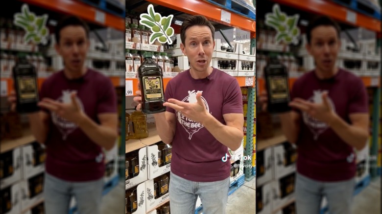 man holding Kirkland olive oil bottle in Costco store