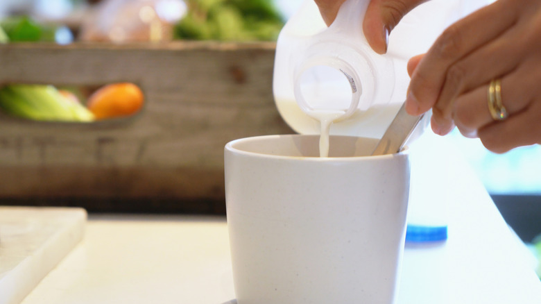 A person pouring milk into a cup.