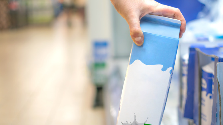 Hand taking milk carton from shelf