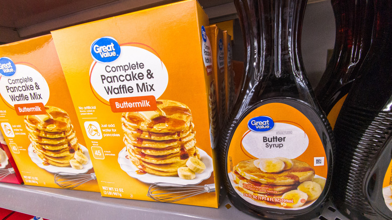 Great Value pancake & waffle mix next to bottles of Great Value butter syrup on a grocery store shelf